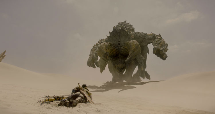 Monster Hunter 2020 Movie Milla Jovovich laying on the ground as a giant monster approaches