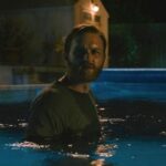 Night Swim 2024 Movie Scene Wyatt Russell as Ray Waller slowly going deeper into the haunted pool to save his family