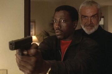 Rising Sun 1993 Movie Scene Sean Connery as John Connor standing behind Wesley Snipes as Web Smith holding a gun in his hand